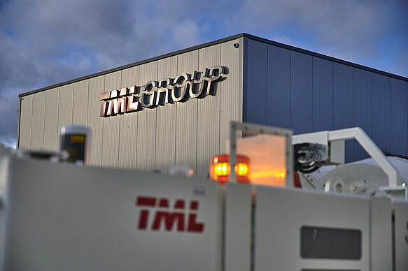 Dieses Bild zeigt die Service Halle der TML Technik, in der das TML Group Logo in 3D hinterleuchtet zu sehen ist. Das Logo ist in der Mitte des Bildes platziert und fügt sich harmonisch in das Gesamtbild ein. Das Hinterleuchten des Logos verleiht dem Bild zusätzlich eine moderne und futuristische Atmosphäre