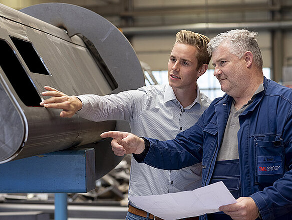 Dos trabajadores realizando un control de calidad en un componente de metal